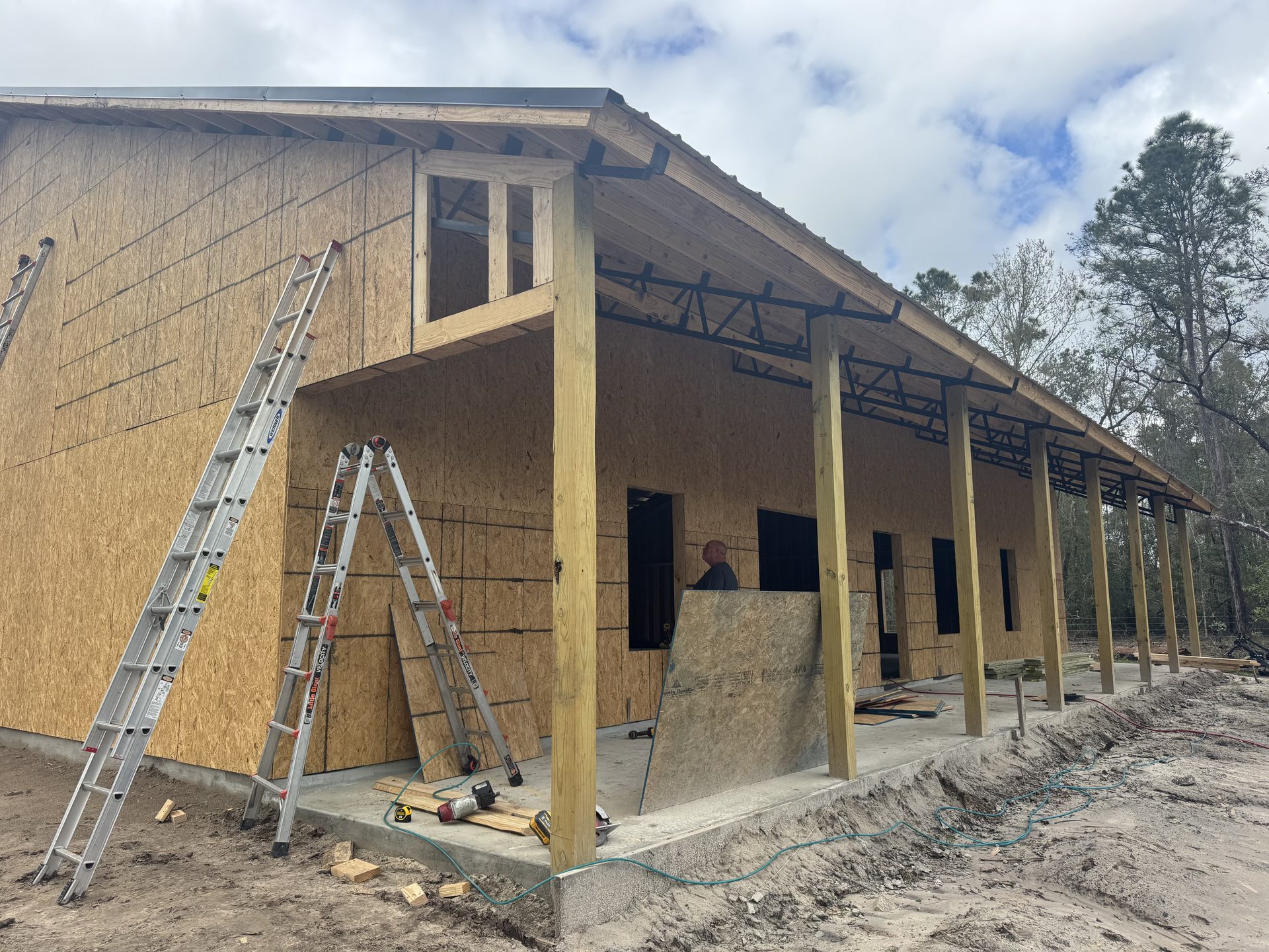 Black metal pole barn under construction with visible framing