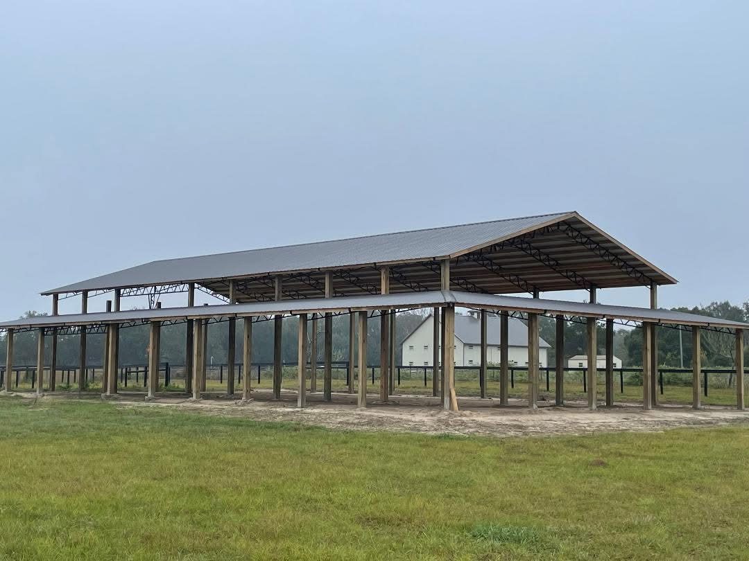 Large commercial pole barn with tan metal siding and open bay