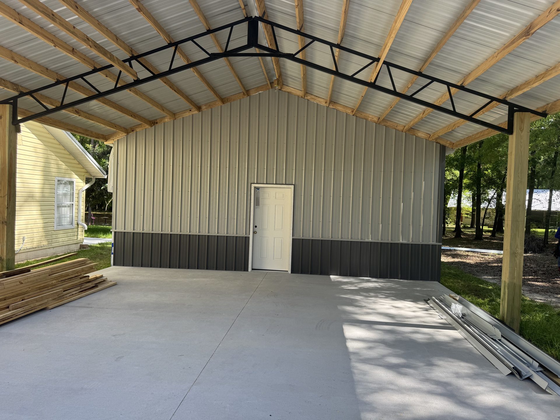 Red metal pole barn with white roll-up door and entry door on open land