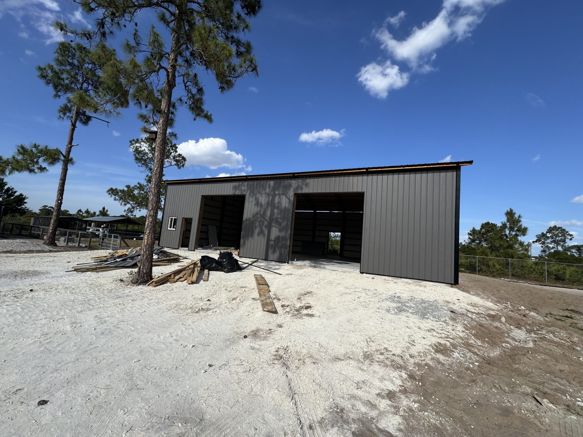 Black enclosed barndominium with covered porch and wood post columns