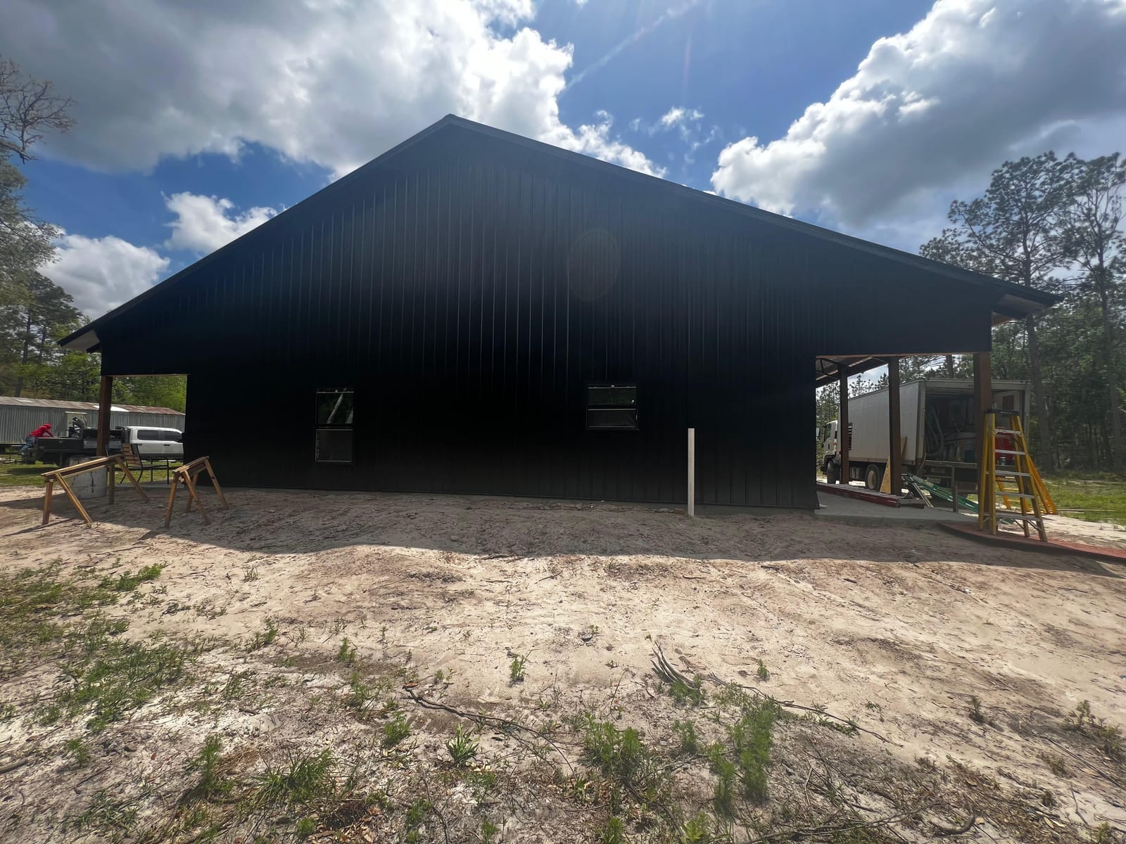 Enclosed Pole Barns — Black gable-end barn under construction