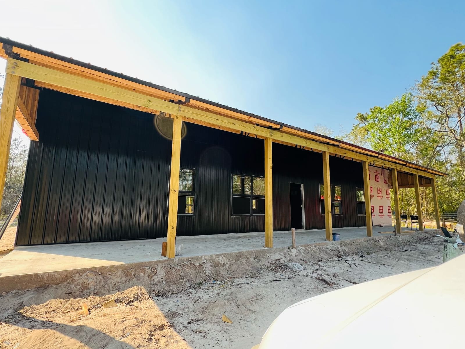 Enclosed Pole Barns — Black barn with wood-post porch