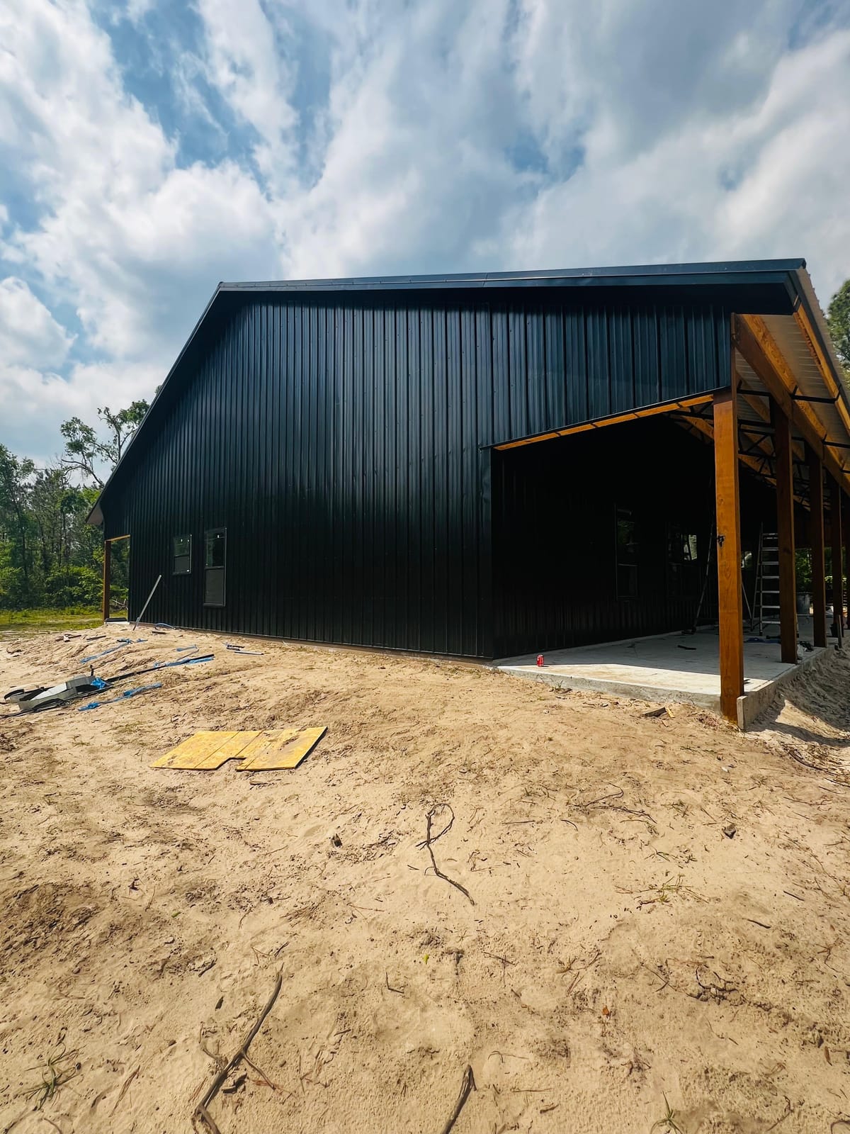 Enclosed Pole Barns — Black barn with side lean-to
