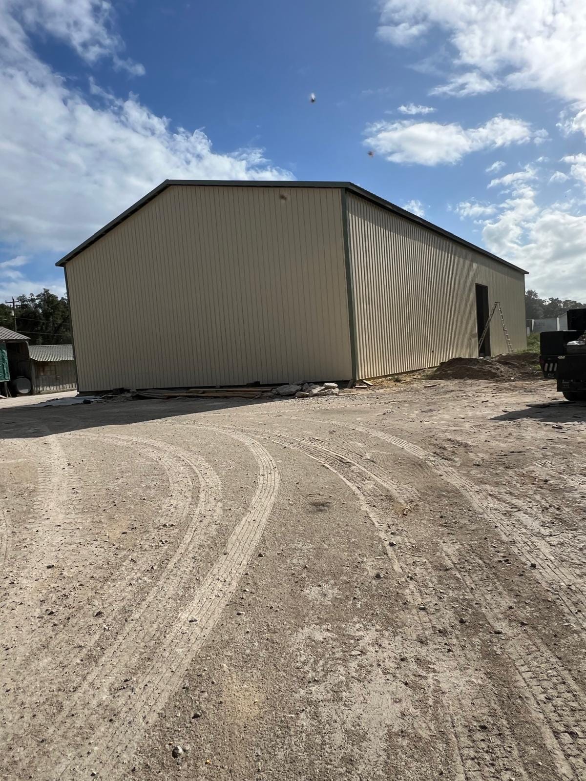 Enclosed Pole Barns — Tan walled workshop on dirt lot