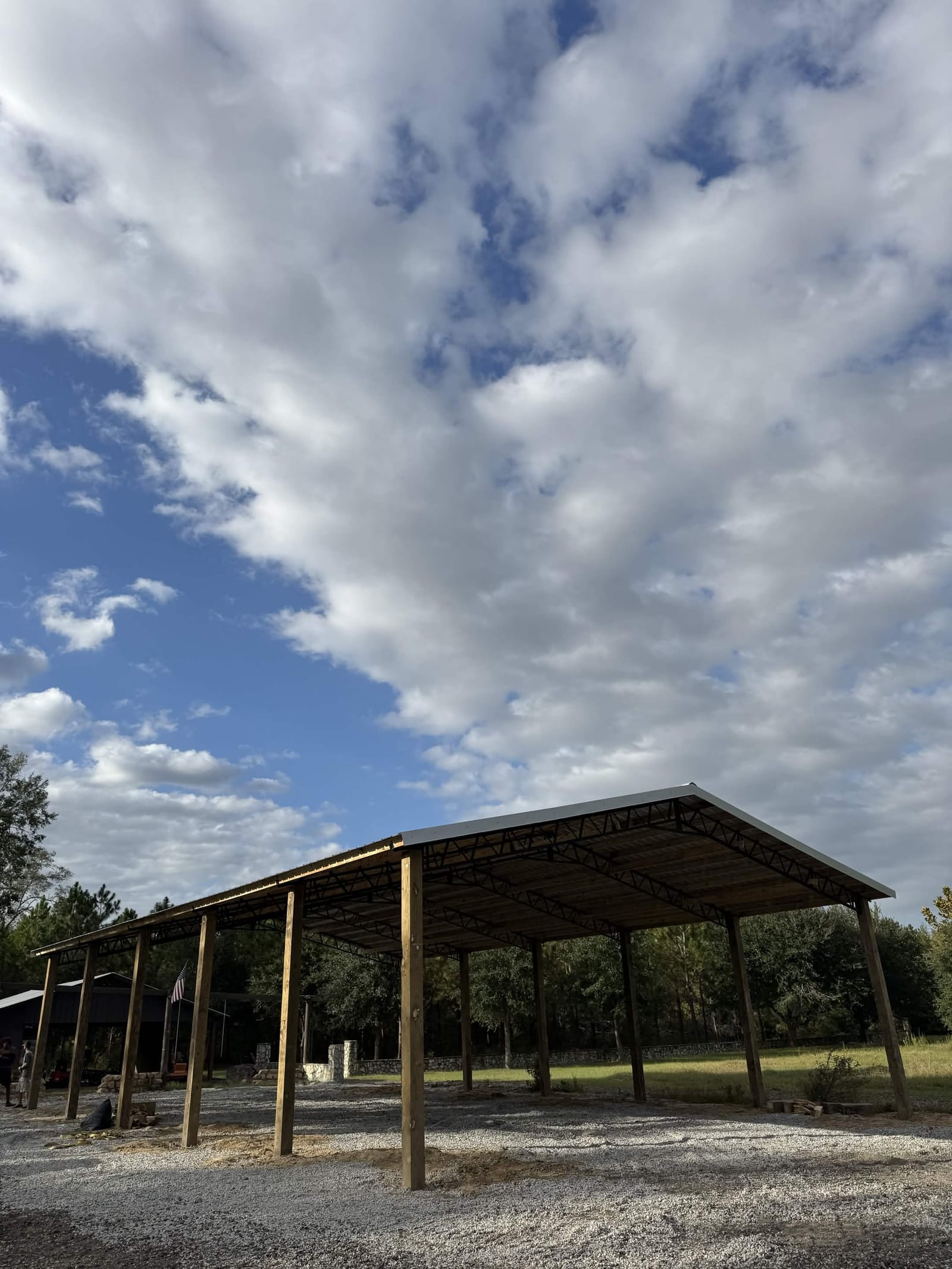Completed pole barn with metal roof under a bright sky
